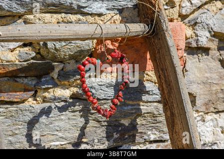 Ein Herz aus Hagebuttenbeeren, die an einer Holzleiter hängen Stockfoto