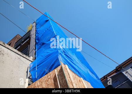 Gerüstnetz oder Gerüstnetz auf Fassadengerüsten. Baustelle und Arbeiter schützen. Verhindern Sie, dass Staub und Schmutz herunterfallen. Blau DE Stockfoto