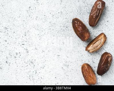 Süße raw Termine auf grauzement Hintergrund. Ganze Termine und Hälfte mit Knochen Datum auf grauem Beton Oberfläche. Zucker freie Alternativen konzept mit Platz fo Stockfoto