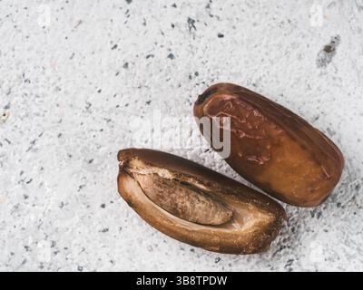 Süße raw Termine auf grauzement Hintergrund. Ganze Termine und Hälfte mit Knochen Datum auf grauem Beton Oberfläche. Zucker freie Alternativen konzept mit Platz fo Stockfoto