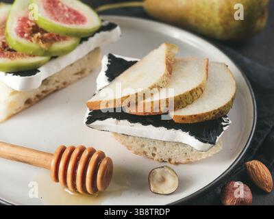 Toast mit schwarzem Camembert-Käse und Birnenscheiben auf dem Teller. Gesunde Snack- oder Frühstücksidee Stockfoto