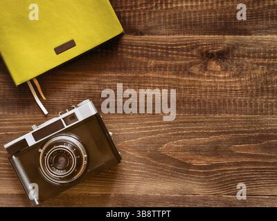 Alte alte Kamera und Notizbuch von oben auf hölzernem Hintergrund Stockfoto