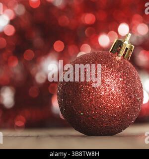 Eine rote Weihnachtskugel auf dem Hintergrund der roten boken Stockfoto
