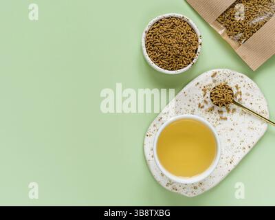 Tasse Buchweizen-Tee auf hellgrünem Hintergrund. Draufsicht auf gesunden Soba-Tee und Grütze von tartary Buchweizen Samen auf grünem Hintergrund. Flach liegend. Kopieren Stockfoto