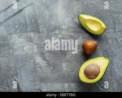 Avocado mit kopieren. Blick von oben auf die Avocado Halbe, Viertel und Avocado Grube auf grauem Hintergrund. Essen Hintergrund Stockfoto
