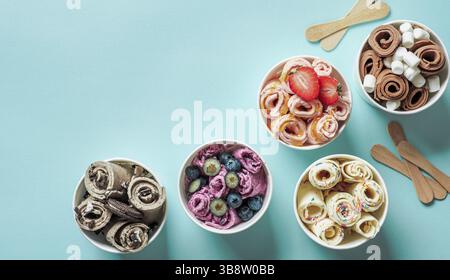 Gerollte Eiscremes in Kegelbechern auf blauem Hintergrund. Verschiedene Eisrollen von oben oder flach. Thailändisches Eis mit Kopierraum für Text oder Stockfoto