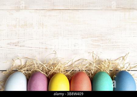 Osterkonzept. Bunte Eier auf weißem Holzhintergrund mit Platz für Text. Draufsicht oder flache Lage Stockfoto