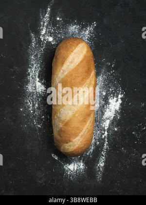 British White Bloomer oder European Baton Brotbrot auf schwarzem Hintergrund. Draufsicht oder flache Lagen. Kopierbereich für Text oder Design. Vertikal Stockfoto
