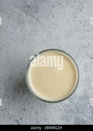Gesundes Getränk goldene Kurkuma Latte in Glas Tasse. Gelber hausgemachter Latte auf grauem Hintergrund. Detox Kurkuma Tee Latte. Copyspace für Text Draufsicht oder f Stockfoto