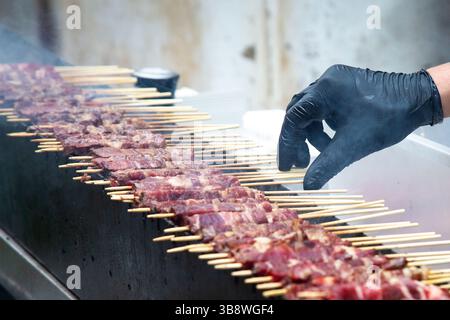 Eine lange Reihe leckeres Fleisch auf Stöcken kocht auf einem Grill Stockfoto