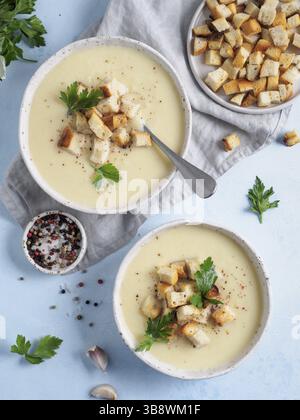 Blumenkohlkartoffelsuppe auf blauer Tischplatte, cremige Blumenkohlsuppe mit gerösteten Brotcroutons. Vegetarisches gesundes Lebensmittelkonzept. Ideen und Rezepte Stockfoto