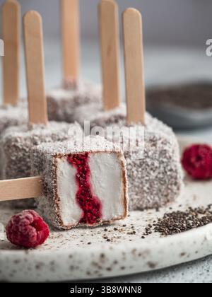 Hausgemachte raw lamington Eis springt auf hellen Hintergrund. Australische süße Nachspeise lamington mit Chia und Himbeeren Marmelade, Schokolade und Kakao. Stockfoto