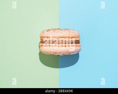 Rosa Makaron auf zwei Farben Papierhintergrund Perfekte französische Makronen oder Makronen auf blauem und grünem Hintergrund. Draufsicht oder flache Lage. Hartes Licht Stockfoto