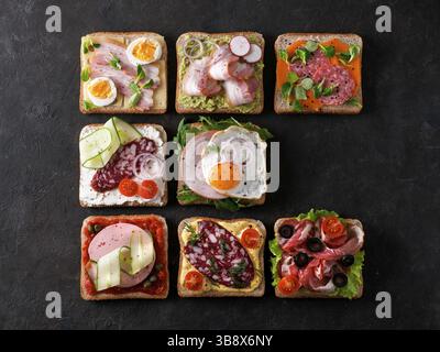 Set aus acht verschiedenen Sandwiches mit Fleisch in quadratischer Form, kopieren Raum für Text. Draufsicht oder flaches Lay. Fleischtoastgerichte auf schwarzem Hintergrund. Id Stockfoto