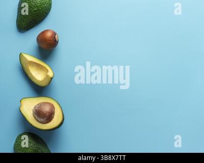 Avocado mit kopieren. Blick von oben auf die Avocado Halbe, Viertel und Avocado Grube auf hellblauem Hintergrund. Essen Hintergrund Stockfoto