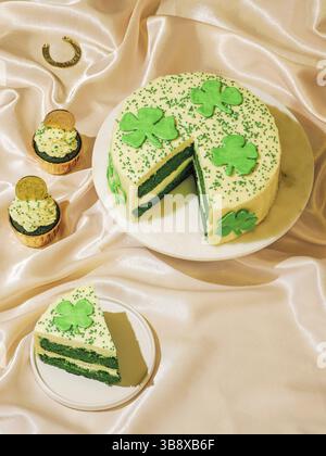 St. Patricks Day Süßes-Food-Konzept. Süße Desserts für die St. Patrick's Day Party - kuchenverzierte Kleeblätter, grüne Samtkuchenbacken, chocolate golden Stockfoto