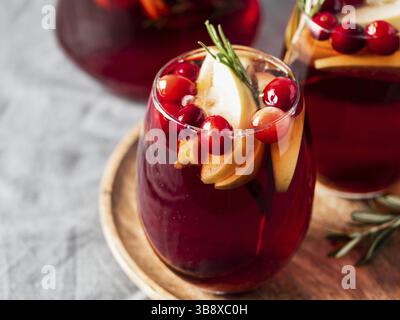 Wintersangria auf Tischplatte mit grauer Leinentischdecke. Gläser Sangria mit Fruchtscheibe, Cranberry und Rosmarin. Platz für Text oder Design kopieren. Hor Stockfoto