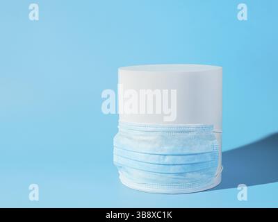 Coronavirus covid-19 minimalistisches Konzept. Weißer Zylinder mit blauer Atemmaske auf blauem Hintergrund. Kopierbereich für Text oder Design Stockfoto