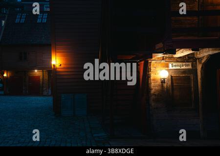 Stimmungsvolle Nachtszenen von der Bryggen Wharf in Bergen, Norwegen, mit gemütlichen Geschäften, beleuchteten Gassen und historischen Holzgebäuden in warmen Lichtern Stockfoto