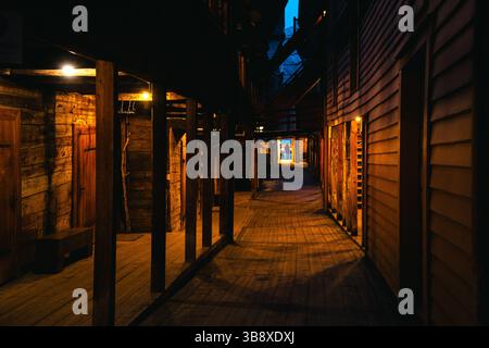 Stimmungsvolle Nachtszenen von der Bryggen Wharf in Bergen, Norwegen, mit gemütlichen Geschäften, beleuchteten Gassen und historischen Holzgebäuden in warmen Lichtern Stockfoto
