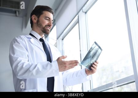 Lächelnder Arzt untersucht Hals-MRT-Untersuchung in Klinik, Tiefwinkelansicht Stockfoto