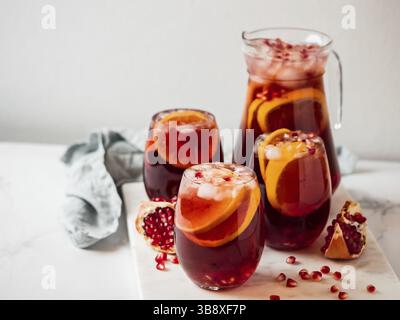 Wintersangria auf Tischplatte mit grauer Leinentischdecke. Juggly von Sangria und Gläser mit Obstscheibe, Cranberry und Rosmarin. Kopieren Sie den Bereich für den tex Stockfoto