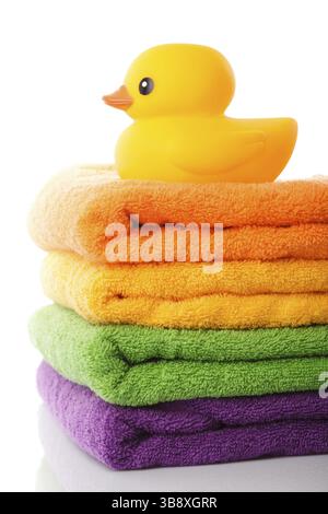 Stapel von farbenfrohe Handtücher und gelbe Gummiente isoliert auf weiss Stockfoto