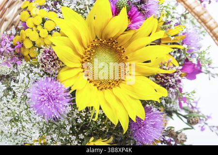 Bouquet von Wiesenblumen und Sonnenblumen im Korb isoliert Stockfoto