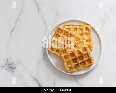 Köstliche herzhafte Keto-Waffeln. Zwei Zutaten schabeln auf Teller auf weißem Marmorgrund. Eier und Parmesan-Käse kohlenhydratarme Waffeln. Draufsicht oder Stockfoto