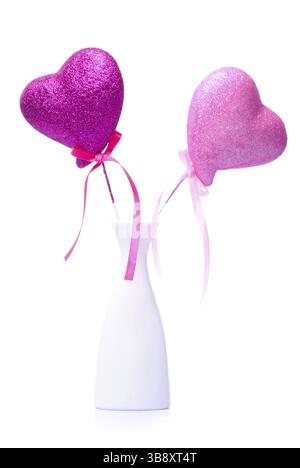 Zwei rosa Herzen mit Schleifen in Vase, isoliert auf weiss Stockfoto