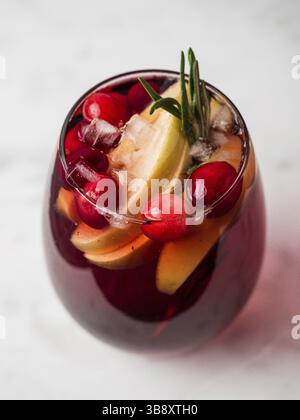 Wintersangria auf Tischplatte mit grauer Tischdecke aus Leinen. Gläser Sangria mit Fruchtscheibe, Preiselbeere und Rosmarin. Vertikal Stockfoto