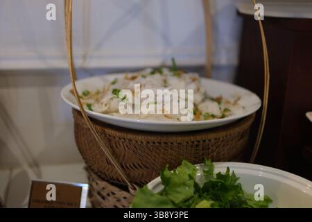 Rosenknödel mit thailändischen Reismehlnudeln oder leicht fermentierten Reisnudeln auf grünem Bananenblatt im Korb. Essen Sie mit Fischcurry und verschiedenen Gemüsesorten. Hochwertige Fotos Stockfoto