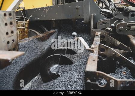 Detaillierte Nahaufnahme der Flügelräder eines Asphaltfertigers, die die kritischen Komponenten für eine gleichmäßige Verteilung und reibungslose Anwendung darstellen Stockfoto