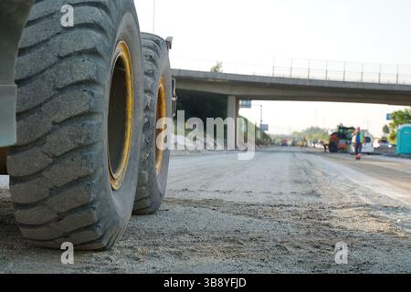 Detaillierte Nahaufnahme eines Motorgraders bei der Arbeit auf einer Autobahnbaustelle, der die Oberfläche für die nächste Phase des Straßenpflasters formt. Stockfoto