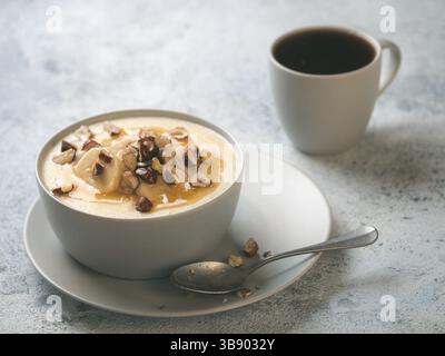 Schüssel mit Mais Grieß Brei mit Banane, Haselnuss und verbrannte Butter Honig. Süße Polenta oder maismehl Brei. Ideen und Rezepte für sehr schnelle Br Stockfoto