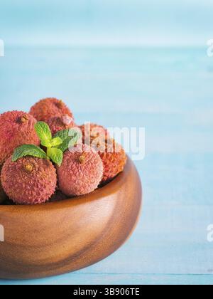 Litschi-Frucht in Tonplatte auf blauem hölzernem Hintergrund Nahaufnahme Stockfoto