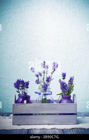 Lavendel in Flaschen, Einrichtung im provance-Stil, Holzkiste auf gehäkelter Tischdecke Stockfoto