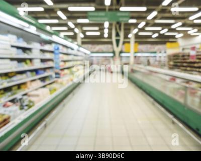 Verschwommener Supermarkt-Gang mit farbenfrohen Regalen mit Waren. Perspektivische Sicht auf den abstrakten Supermarktgang mit Kopierraum in der Mitte Stockfoto