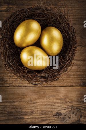 Goldene Eier im Nest auf hölzernem Hintergrund mit Text Stockfoto