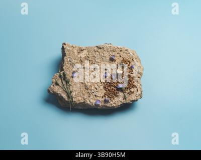 Leinsamen und Leinöl auf Stein. Braune Leinensamen, Leinsamenöl und blaue Leinenblüten auf altem grauen Felsen auf blauem Hintergrund. Speicherplatz kopieren. Draufsicht oder Stockfoto