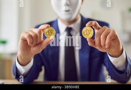 Nahaufnahme eines Mannes in weißer Maske, der goldene Bitcoins hält. Stockfoto