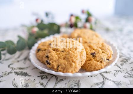 Detail einer kleinen Korbplatte mit einigen köstlichen Schokoladenchips glutenfreie Kekse dekoriert mit Blumen. Sie sind frisch, gebacken und handgemacht. Die Stockfoto