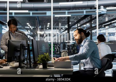 Verärgerter Ingenieur im Rechenzentrum, der persönliche Gegenstände an der Workstation verpackt, nachdem er durch KI ersetzt wurde. Techniker, der Gegenstände vom Schreibtisch des Server-Hubs entfernt, ausgelöst durch künstliche Intelligenz Stockfoto