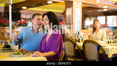 Fröhliches, interrassisches Paar für Erwachsene beim Abendessen im Restaurant Stockfoto
