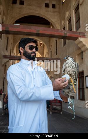 Ein arabischer Mann, der einen Falken in Souq Waqif hält, im Falkenschulungssouk in Doha, Katar. Stockfoto