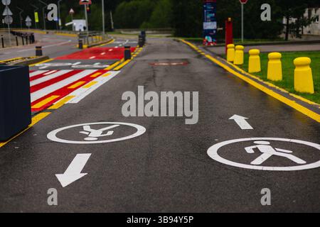 Ein ausgewiesener Fußgänger- und Fahrradweg ist mit Schildern und Linien für die Sicherheit auf der Straße gekennzeichnet. Die Markierungen und Richtungszeichen auf dem Asphalt. Stockfoto