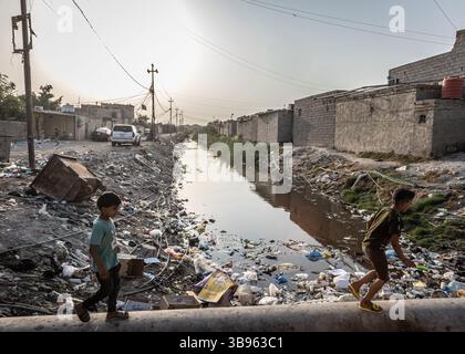 30. Oktober 2021, Basra, Irak: Kinder spielen an einem der Kanäle Basras. Hunderttausende von Menschen, oft die am stärksten benachteiligten, leben an diesen Senkspulen. Die Stadt und ihre Infrastruktur befinden sich heute in Ruinen, die von Korruption und weitverbreiteter Vernachlässigung geplagt sind. Irak: In Basra vergiften Klima- und politische Krisen die Bevölkerung. Es wurde einst als "Venedig des Nahen Ostens" bezeichnet. Angesichts der globalen Erwärmung, der Dämme in den Nachbarländern (Türkei und Iran) und der staatlichen Nachlässigkeit hat die irakische Provinz Basra heute mit einem sehr ernsten Wasserdefizit zu kämpfen. Die Gesundheitskrise Stockfoto