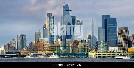 Die pulsierende Skyline von New York City bietet eine Mischung aus modernen Wolkenkratzern und älteren Gebäuden vor einem bewölkten Himmel. Boote können auf dem Wasser im gesehen werden Stockfoto