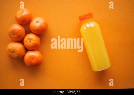Frisch gepresster Orangensaft und reife Orangen auf einer lebendigen Oberfläche Stockfoto