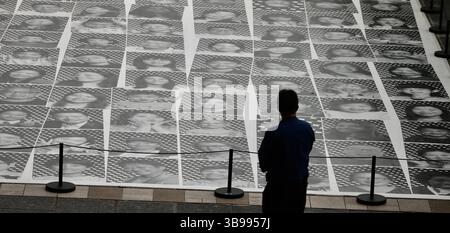 27. April 2023, HONGKONG, CHINA: In Hongkong beobachtet ein Mann die öffentliche Ausstellung von 450 lächelnden Gesichtern Hong Kongers auf monochromen Drucken außerhalb von Harbour City. Eines der globalen Projekte des französischen Künstlers JR mit dem Titel [ Inside Out : Harbour and the City ] wird derzeit öffentlich gezeigt und zeigt lächelnde Gesichter von Bürgern Hongkongs nach der Pandemie.27.April 2023Hong Kong.ZUMA/Liau Chung-ren (Kreditbild: © Liau Chung-ren/ZUMA Press Wire) Stockfoto